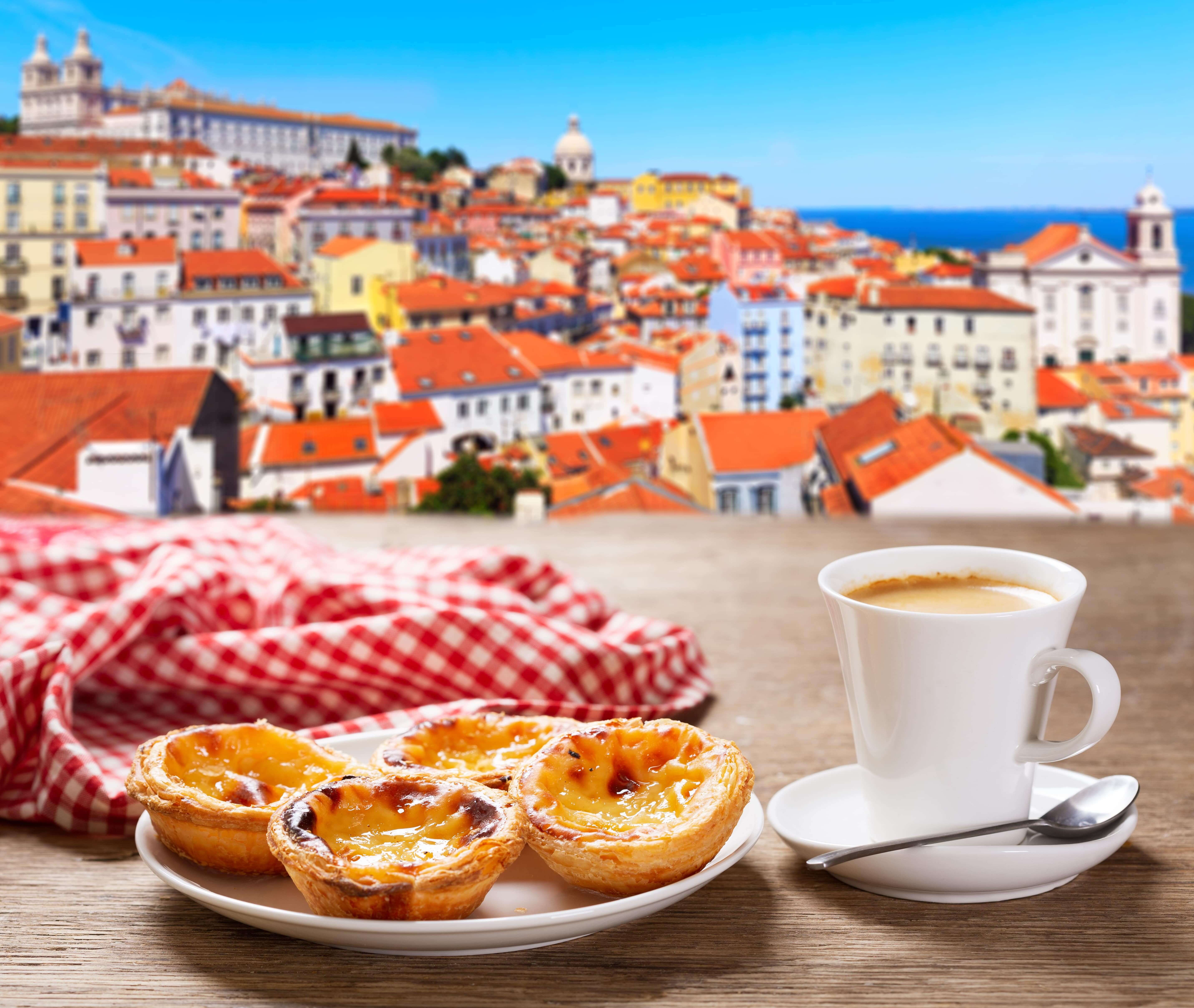 cup of coffee and plate of traditional portuguese pastries - Pastel de nata, over Alfama district, lisbon, Portugal.